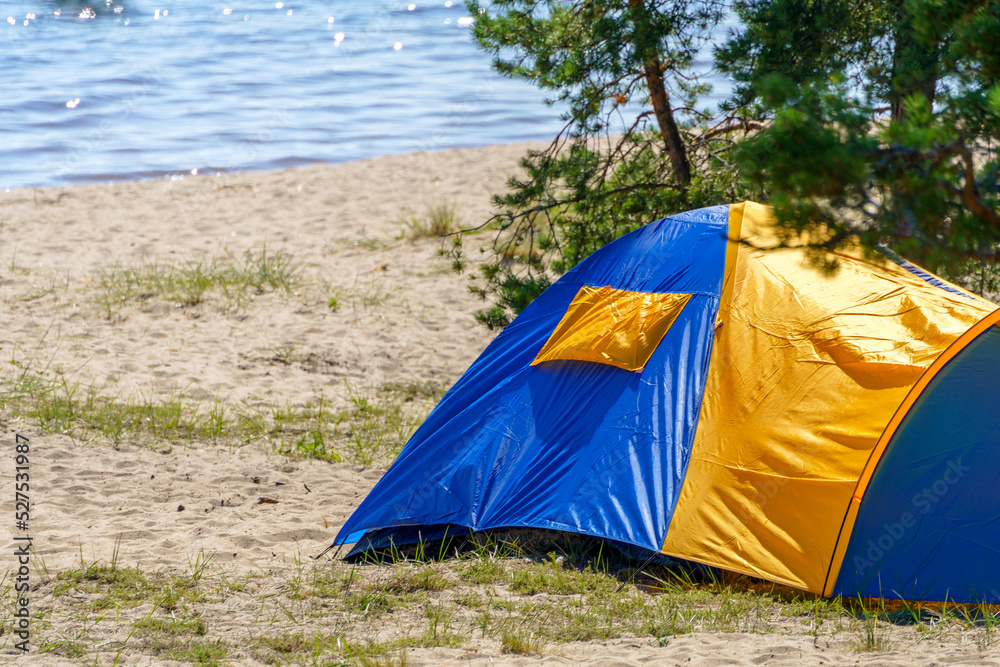 Tourist blue tent on the lake. Journey to the wild places of nature.