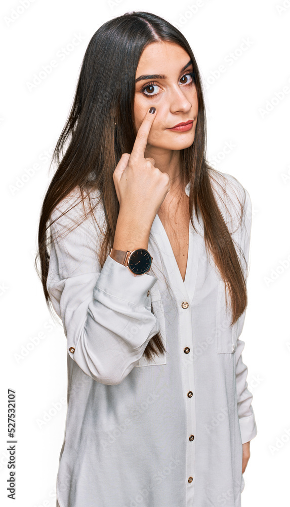 Young beautiful woman wearing casual white shirt pointing to the eye watching you gesture, suspicious expression Young beautiful woman wearing casual white shirt pointing to the eye watching you gesture, suspicious expression
