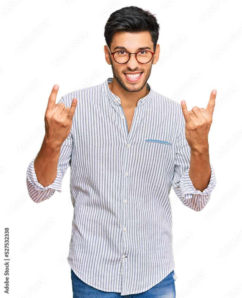 Young handsome man wearing casual clothes and glasses shouting with crazy expression doing rock symbol with hands up. music star. heavy concept. Young handsome man wearing casual clothes and glasses shouting with crazy expression doing rock symbol with hands up. music star. heavy concept.