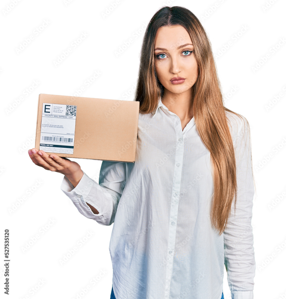 Beautiful caucasian woman holding delivery package thinking attitude and sober expression looking self confident Beautiful caucasian woman holding delivery package thinking attitude and sober expression looking self confident