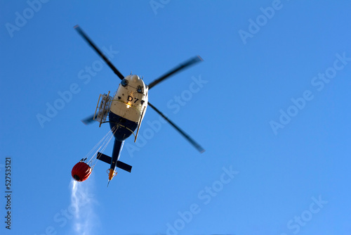 Helicopter putting out a mountain fire, with a bag of water