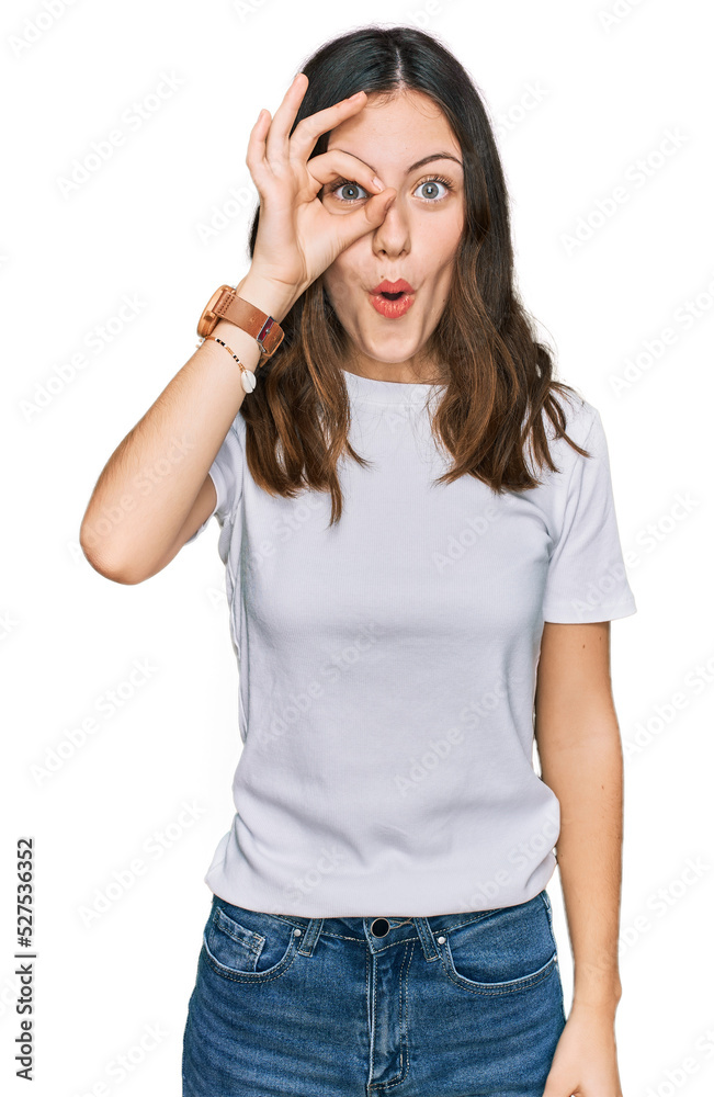 Young beautiful woman wearing casual white t shirt doing ok gesture shocked with surprised face, eye looking through fingers. unbelieving expression. Young beautiful woman wearing casual white t shirt doing ok gesture shocked with surprised face, eye looking through fingers. unbelieving expression.