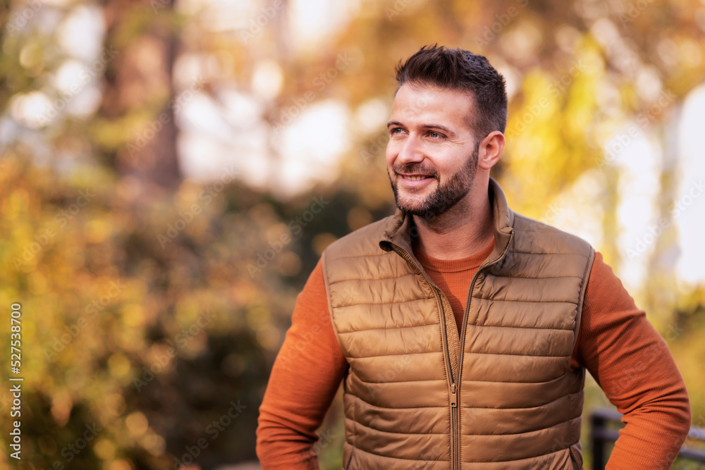 Confident man standign outside in the partk at autumn