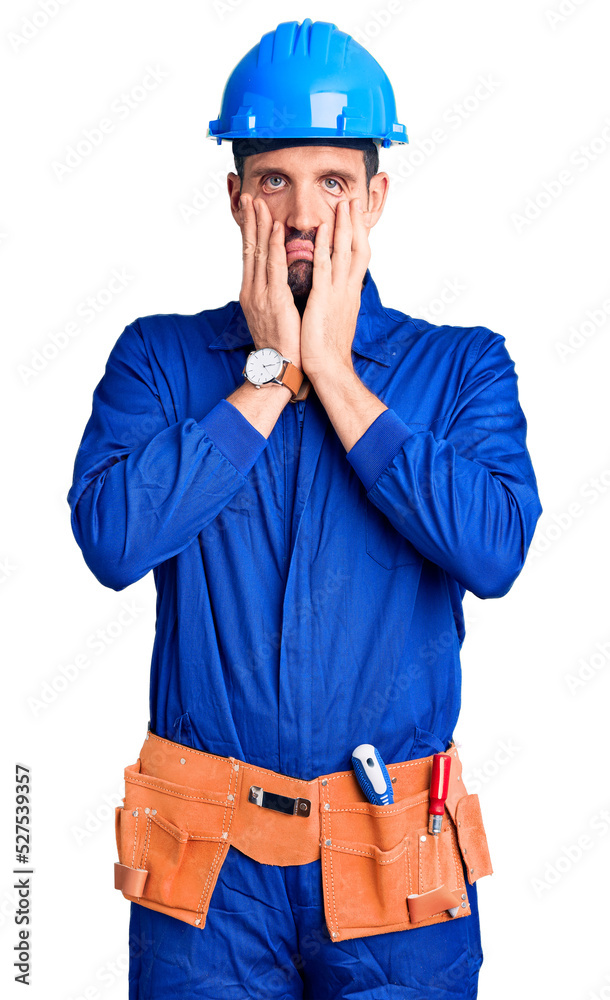 Young handsome man wearing worker uniform and hardhat worried and stressed about a problem with hand on forehead, nervous and anxious for crisis Young handsome man wearing worker uniform and hardhat worried and stressed about a problem with hand on forehead, nervous and anxious for crisis