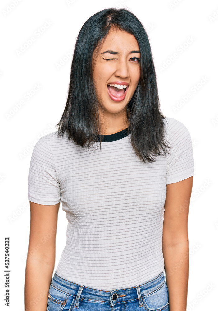 Beautiful asian young woman wearing casual white t shirt winking looking at the camera with sexy expression, cheerful and happy face. Beautiful asian young woman wearing casual white t shirt winking looking at the camera with sexy expression, cheerful and happy face.