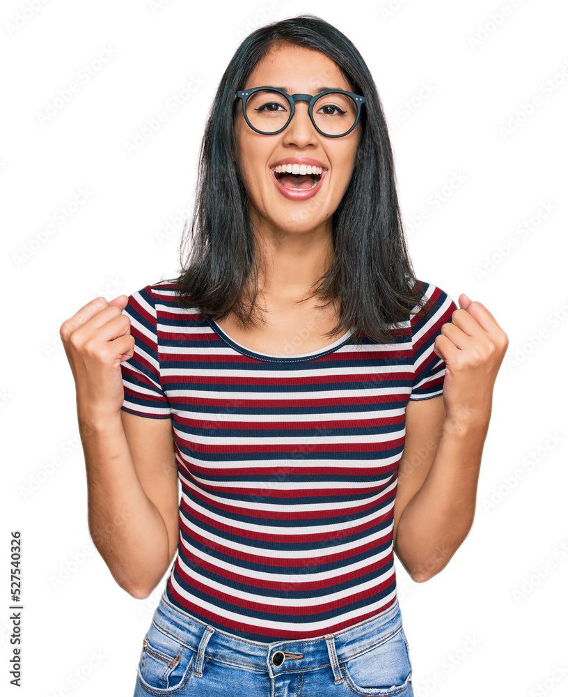 Beautiful asian young woman wearing casual clothes and glasses celebrating surprised and amazed for success with arms raised and open eyes. winner concept. Beautiful asian young woman wearing casual clothes and glasses celebrating surprised and amazed for success with arms raised and open eyes. winner concept.