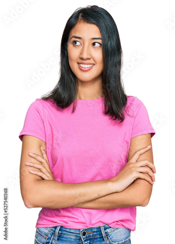 Beautiful asian young woman wearing casual pink t shirt smiling looking to the side and staring away thinking.
