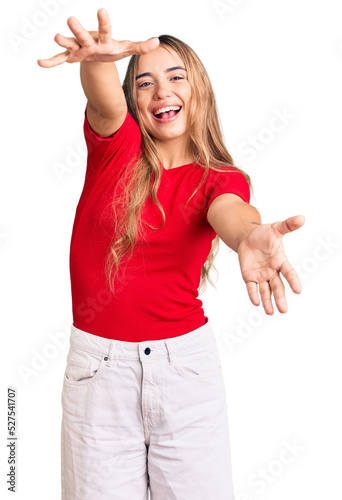 Young beautiful blonde woman wearing casual clothes looking at the camera smiling with open arms for hug. cheerful expression embracing happiness. photo