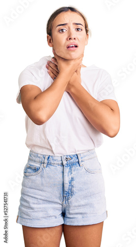 Young beautiful blonde woman wearing casual white tshirt shouting and suffocate because painful strangle. health problem. asphyxiate and suicide concept. photo