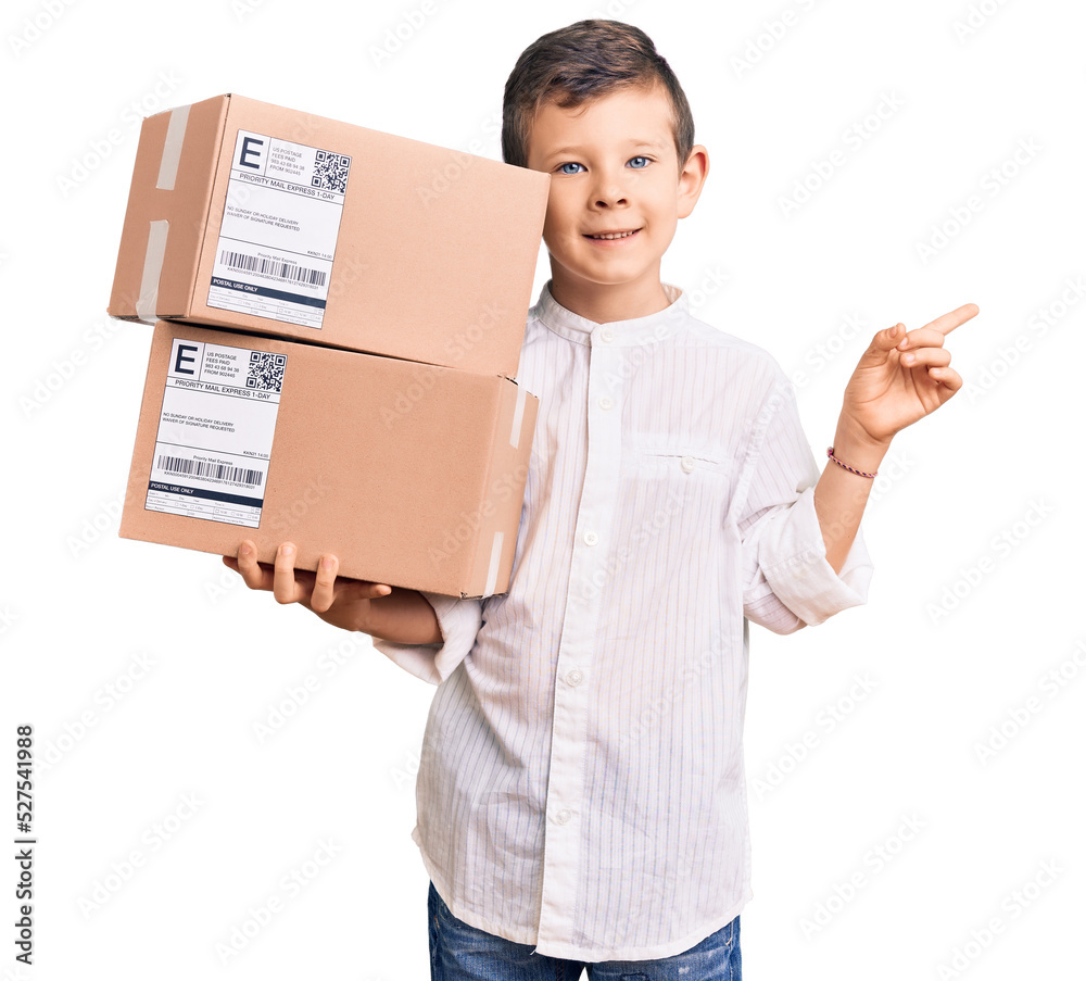 Cute blond kid holding delivery package smiling happy pointing with hand and finger to the side Cute blond kid holding delivery package smiling happy pointing with hand and finger to the side