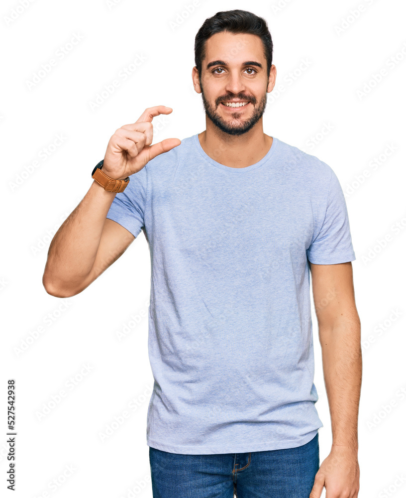Young hispanic man wearing casual clothes smiling and confident gesturing with hand doing small size sign with fingers looking and the camera. measure concept. Young hispanic man wearing casual clothes smiling and confident gesturing with hand doing small size sign with fingers looking and the camera. measure concept.
