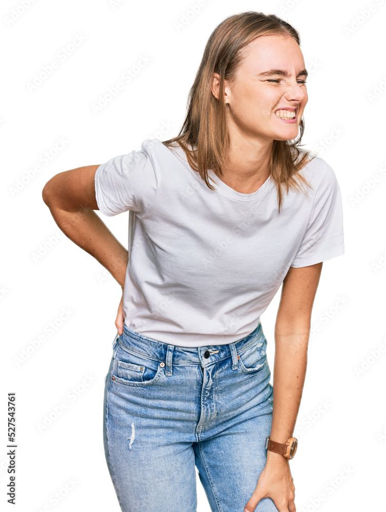 Beautiful young blonde woman wearing casual white t shirt suffering of backache, touching back with hand, muscular pain Beautiful young blonde woman wearing casual white t shirt suffering of backache, touching back with hand, muscular pain