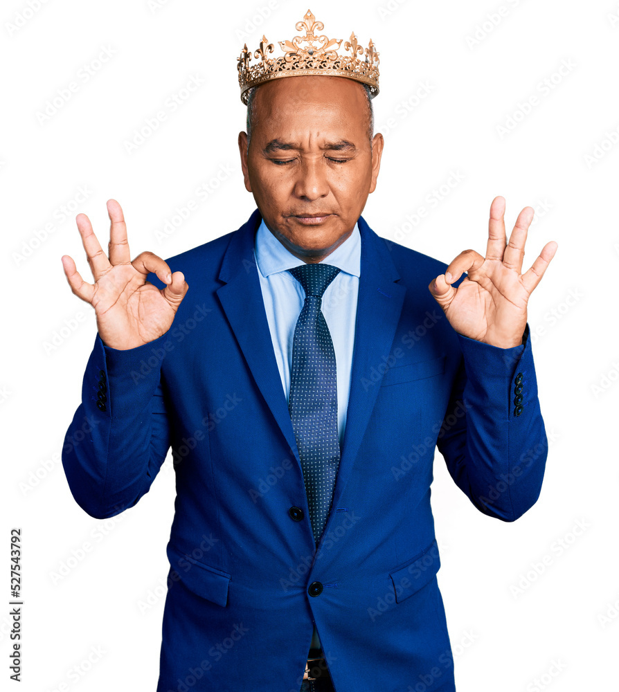 Hispanic middle age man wearing king crown relax and smiling with eyes closed doing meditation gesture with fingers. yoga concept. Hispanic middle age man wearing king crown relax and smiling with eyes closed doing meditation gesture with fingers. yoga concept.