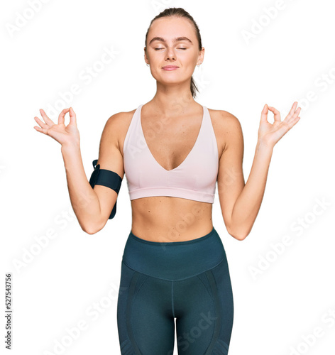 Beautiful young blonde woman wearing sportswear and arm band relax and smiling with eyes closed doing meditation gesture with fingers. yoga concept. © Krakenimages.com