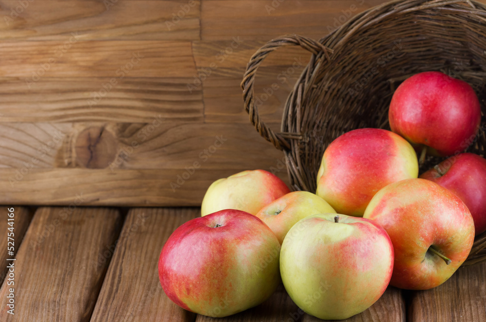 Close-up view of red apples spill out of the basket on wooden background