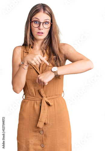 Young beautiful blonde woman wearing casual clothes and glasses in hurry pointing to watch time, impatience, upset and angry for deadline delay