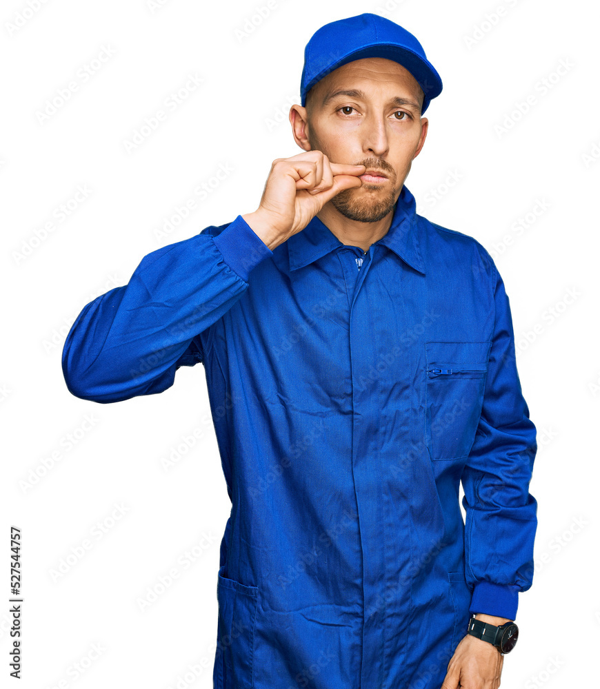 Bald man with beard wearing builder jumpsuit uniform mouth and lips shut as zip with fingers. secret and silent, taboo talking