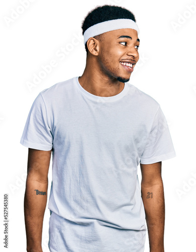 Young african american man wearing sportswear looking away to side with smile on face, natural expression. laughing confident.