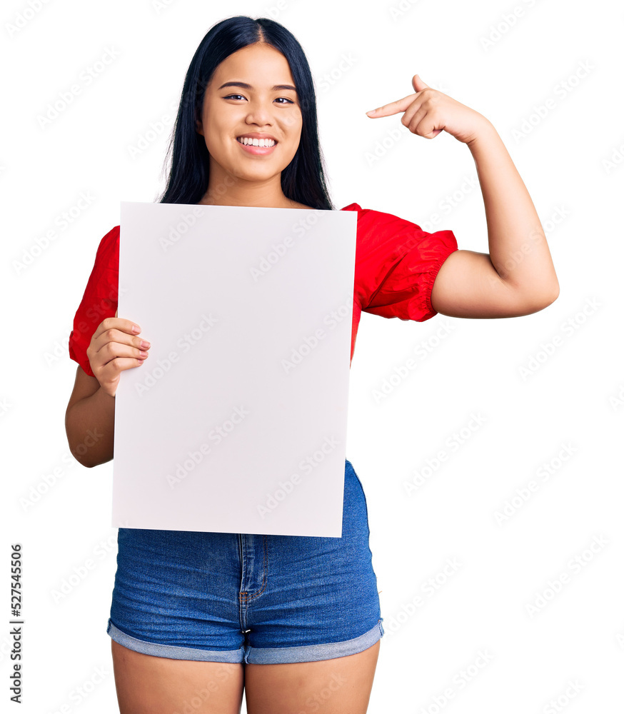 Young beautiful asian girl holding blank empty banner pointing finger to one self smiling happy and proud Young beautiful asian girl holding blank empty banner pointing finger to one self smiling happy and proud