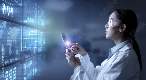 Female chemist or doctor tapping on digital tablet displaying scientific experiment data and charts on a virtual screen in lab. Biochemical and medical industry research.