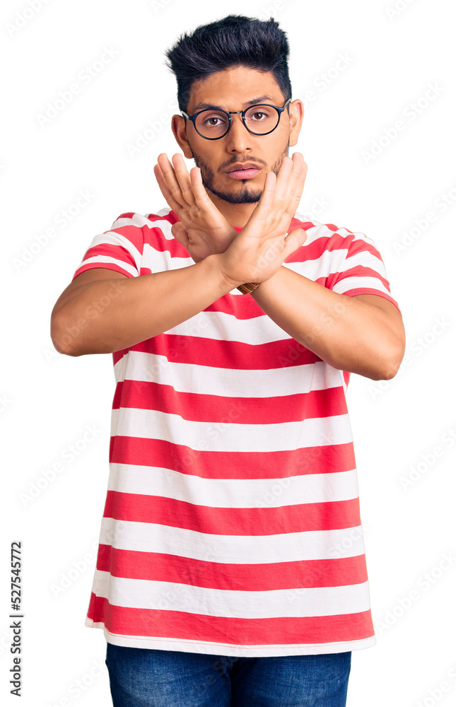 Handsome latin american young man wearing casual clothes and glasses rejection expression crossing arms doing negative sign, angry face Handsome latin american young man wearing casual clothes and glasses rejection expression crossing arms doing negative sign, angry face