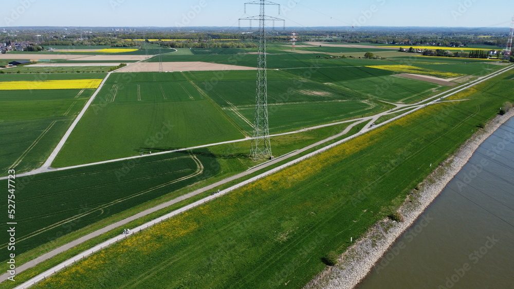 View from sky over rapeseed fields with power lines and fields and river rhine krefeld northrhine westphalia germany