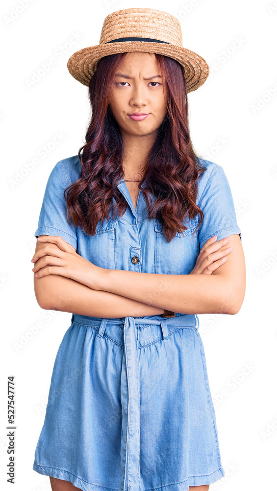 Young beautiful chinese girl wearing summer hat skeptic and nervous, disapproving expression on face with crossed arms. negative person. Young beautiful chinese girl wearing summer hat skeptic and nervous, disapproving expression on face with crossed arms. negative person.