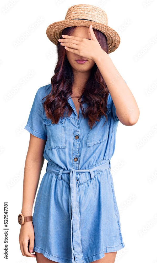Young beautiful chinese girl wearing summer hat covering eyes with hand, looking serious and sad. sightless, hiding and rejection concept Young beautiful chinese girl wearing summer hat covering eyes with hand, looking serious and sad. sightless, hiding and rejection concept