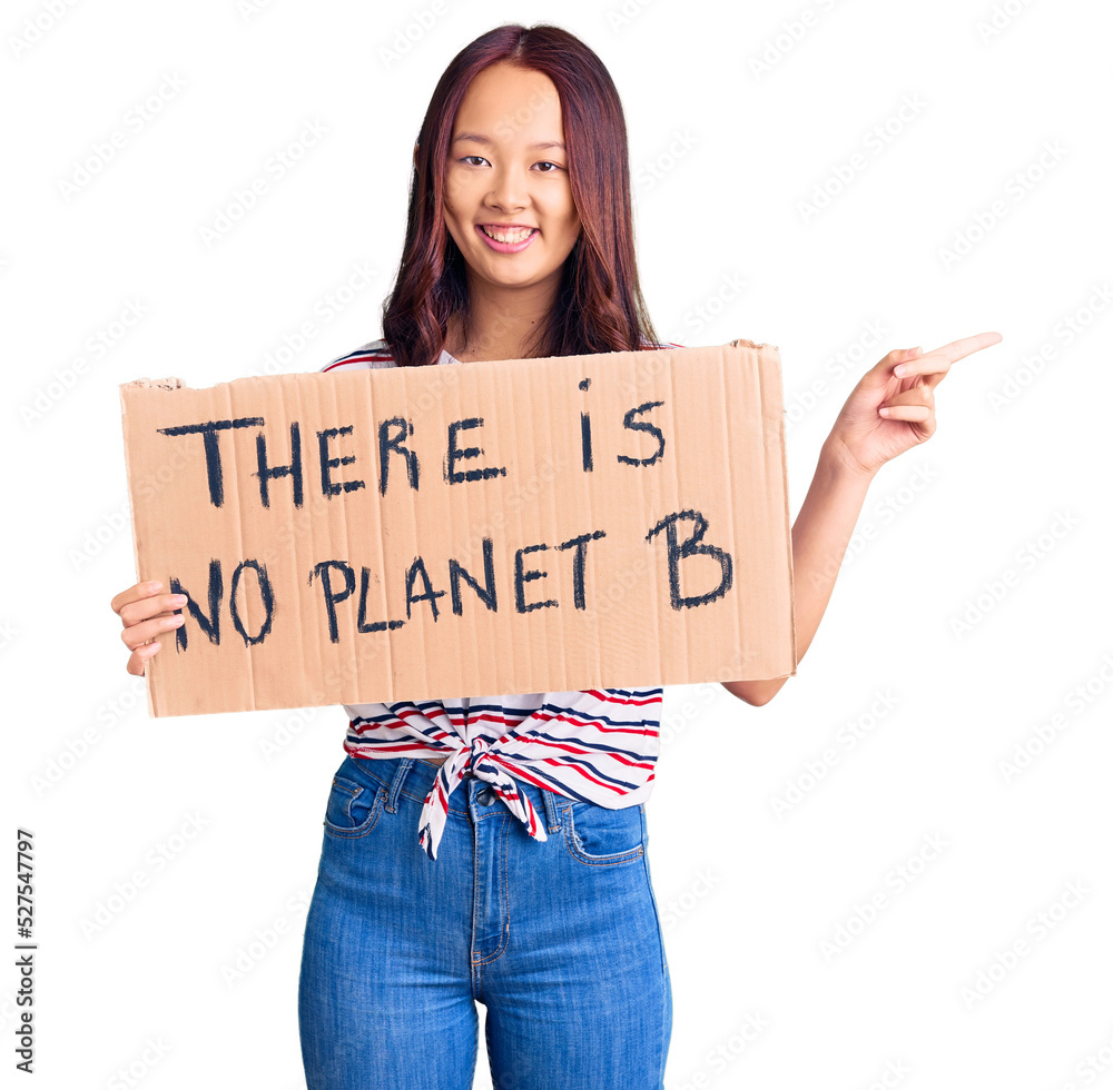 Young beautiful chinese girl holding there is no planet b banner smiling happy pointing with hand and finger to the side Young beautiful chinese girl holding there is no planet b banner smiling happy pointing with hand and finger to the side