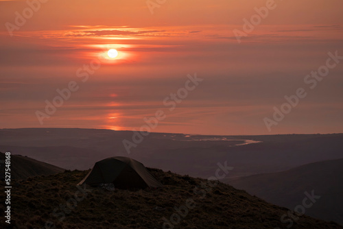 A wild camping tent high in the mountains at sunset