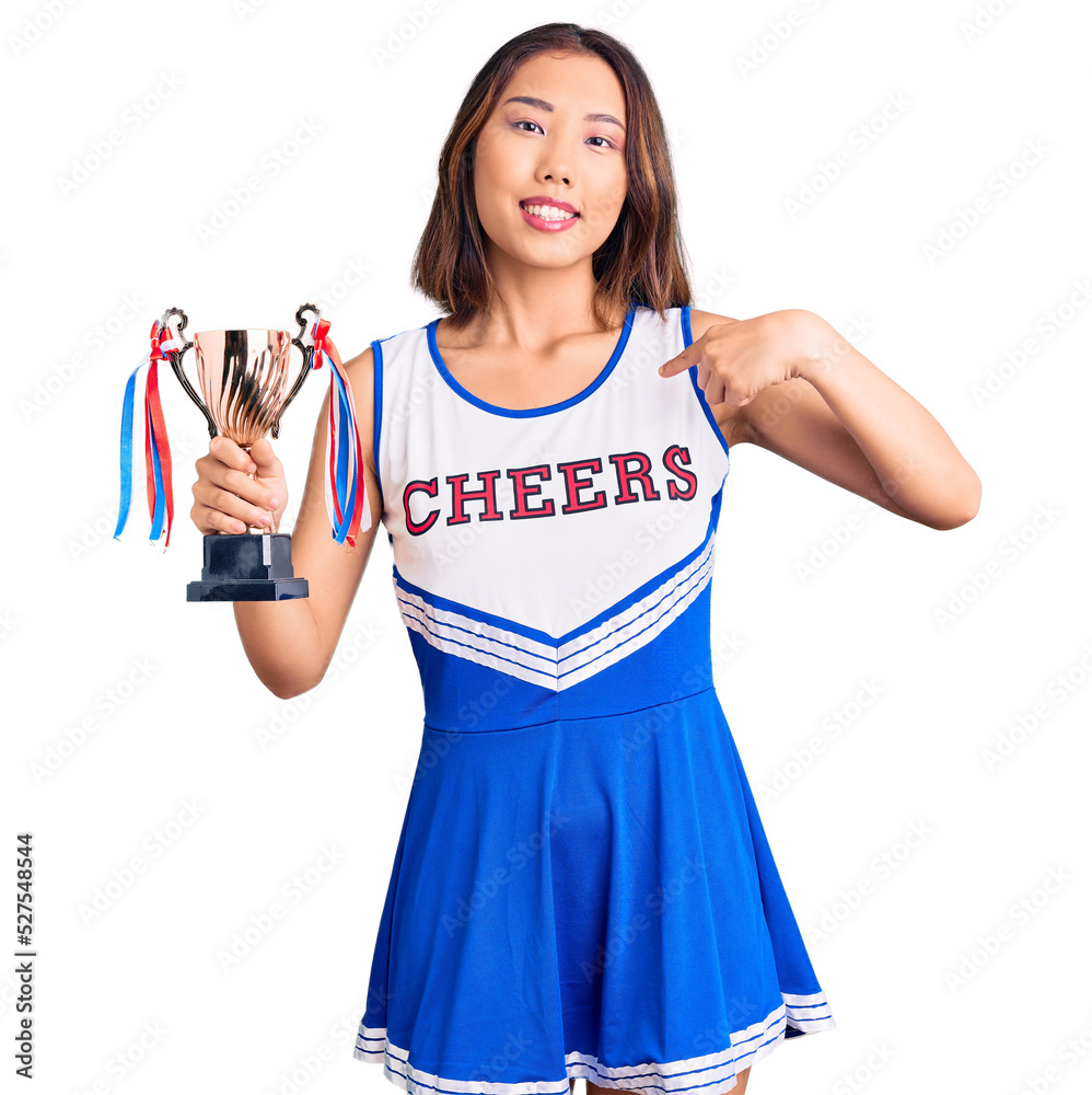 Youn beautiful asian girl wearing cheerleader uniform holding champion trophy pointing finger to one self smiling happy and proud Youn beautiful asian girl wearing cheerleader uniform holding champion trophy pointing finger to one self smiling happy and proud