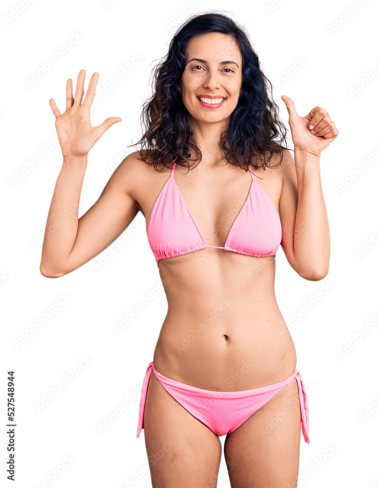 Young beautiful hispanic woman wearing bikini showing and pointing up with fingers number six while smiling confident and happy. Young beautiful hispanic woman wearing bikini showing and pointing up with fingers number six while smiling confident and happy.