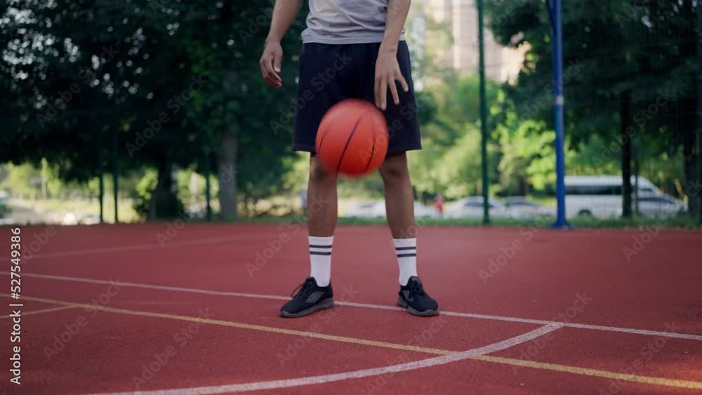 Closeup of black athlete bouncing the ball on court in park, urban lifestyle Closeup of black athlete bouncing the ball on court in park, urban lifestyle