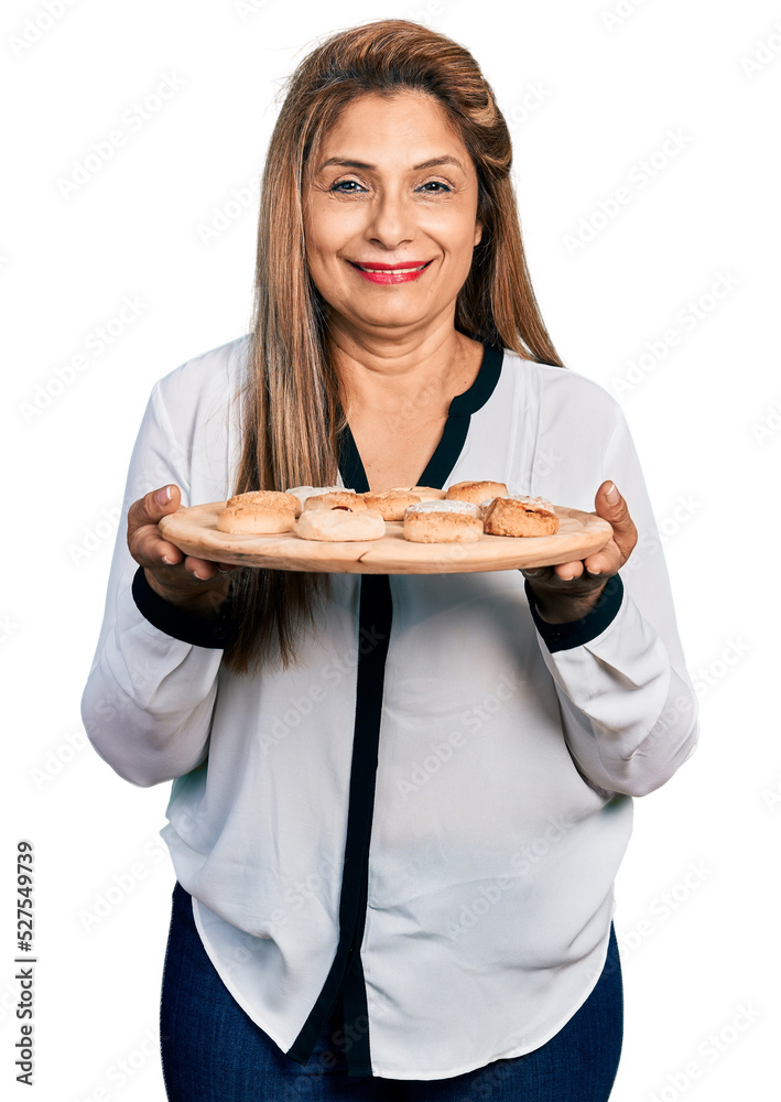 Middle age latin woman eating pastries smiling with a happy and cool smile on face. showing teeth. Middle age latin woman eating pastries smiling with a happy and cool smile on face. showing teeth.
