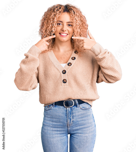 Young blonde woman with curly hair wearing casual winter jumper smiling cheerful showing and pointing with fingers teeth and mouth. dental health concept.