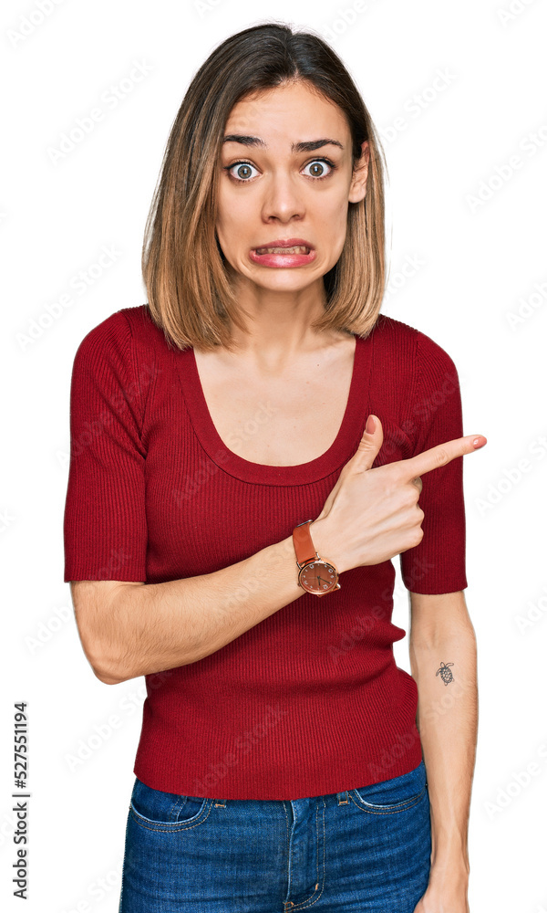 Young blonde girl wearing casual clothes pointing aside worried and nervous with forefinger, concerned and surprised expression Young blonde girl wearing casual clothes pointing aside worried and nervous with forefinger, concerned and surprised expression