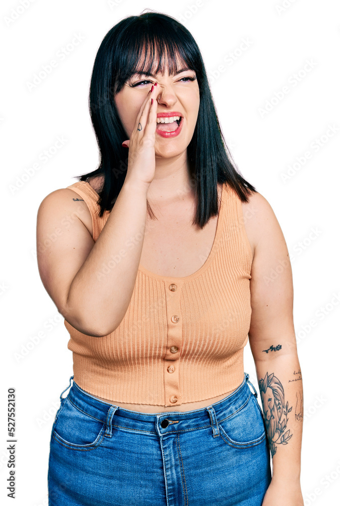 Young hispanic plus size woman wearing casual clothes shouting and screaming loud to side with hand on mouth. communication concept. Young hispanic plus size woman wearing casual clothes shouting and screaming loud to side with hand on mouth. communication concept.