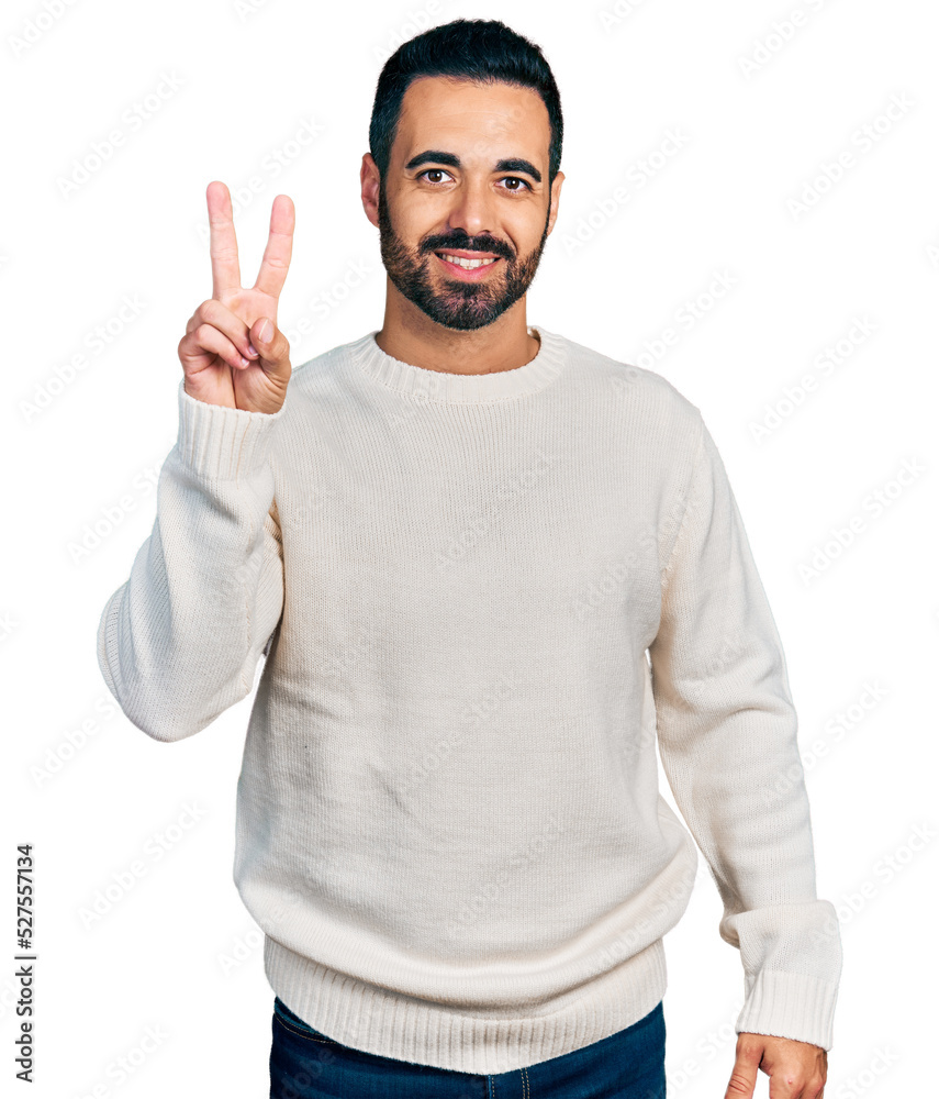 Young hispanic man with beard wearing casual white sweater showing and pointing up with fingers number two while smiling confident and happy. Young hispanic man with beard wearing casual white sweater showing and pointing up with fingers number two while smiling confident and happy.