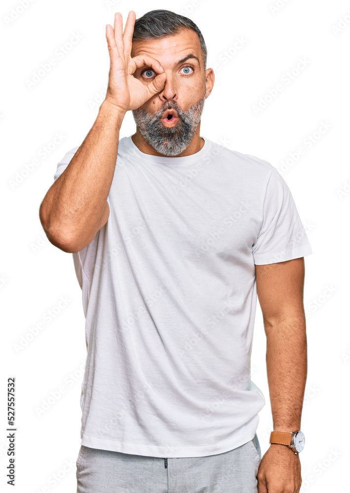 Middle age handsome man wearing casual white tshirt doing ok gesture shocked with surprised face, eye looking through fingers. unbelieving expression. Middle age handsome man wearing casual white tshirt doing ok gesture shocked with surprised face, eye looking through fingers. unbelieving expression.