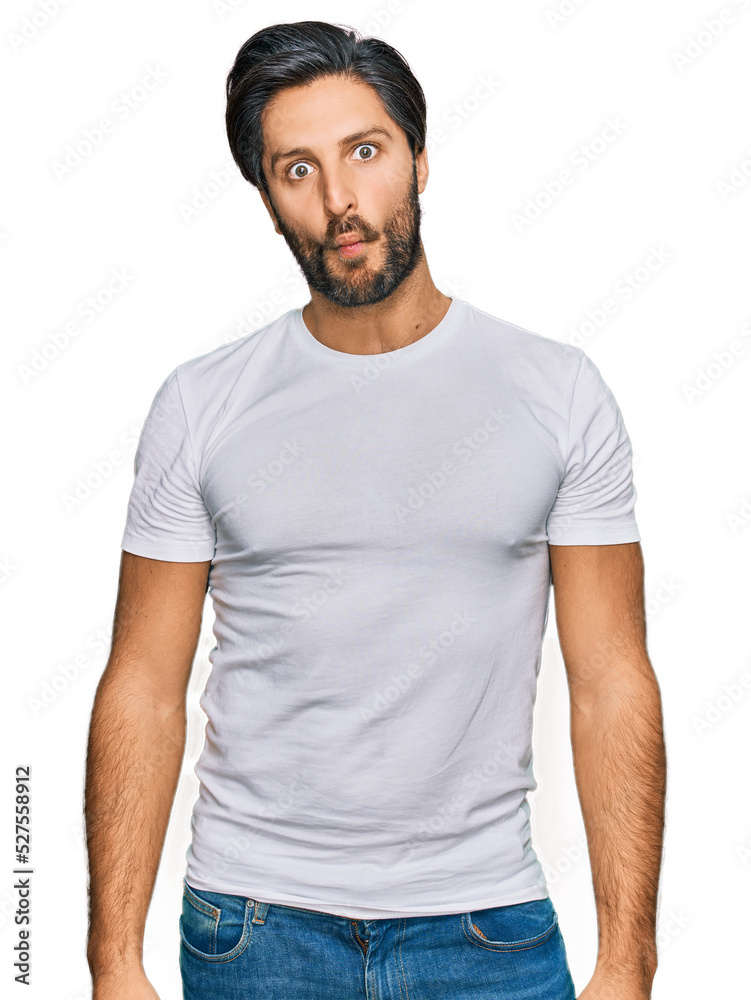 Young hispanic man wearing casual white t shirt making fish face with lips, crazy and comical gesture. funny expression. Young hispanic man wearing casual white t shirt making fish face with lips, crazy and comical gesture. funny expression.