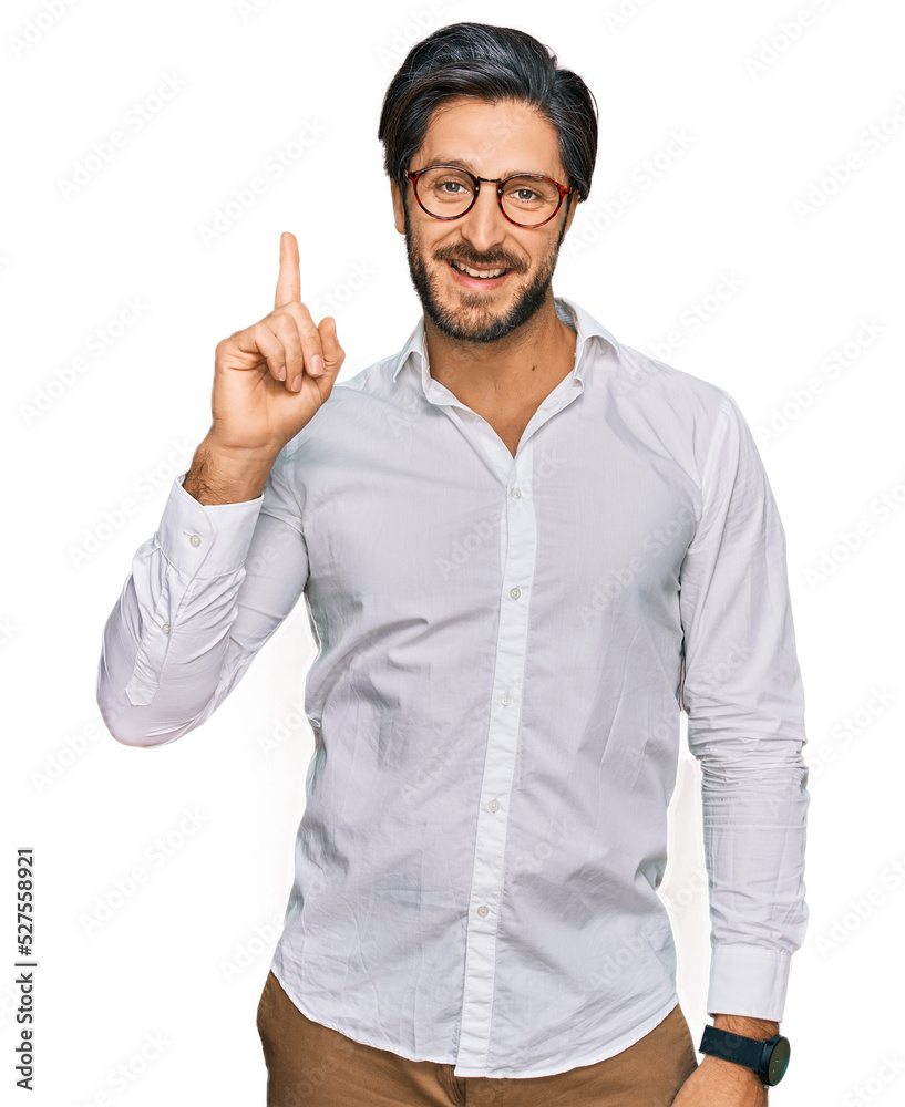Young hispanic man wearing business shirt and glasses showing and pointing up with finger number one while smiling confident and happy. Young hispanic man wearing business shirt and glasses showing and pointing up with finger number one while smiling confident and happy.