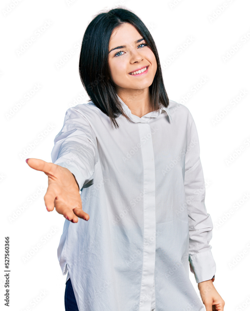 Young brunette woman with blue eyes wearing oversize white shirt smiling cheerful offering palm hand giving assistance and acceptance. Young brunette woman with blue eyes wearing oversize white shirt smiling cheerful offering palm hand giving assistance and acceptance.