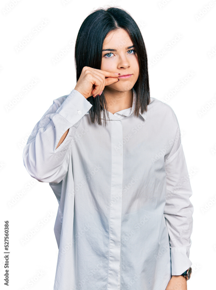 Young brunette woman with blue eyes wearing oversize white shirt mouth and lips shut as zip with fingers. secret and silent, taboo talking Young brunette woman with blue eyes wearing oversize white shirt mouth and lips shut as zip with fingers. secret and silent, taboo talking