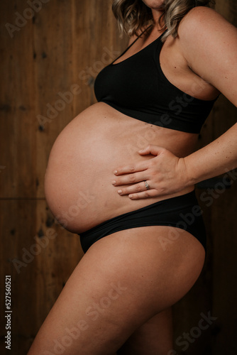 Close up side view of pregnant woman touching her tummy.