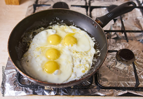 Four eggs are fried in a black pan