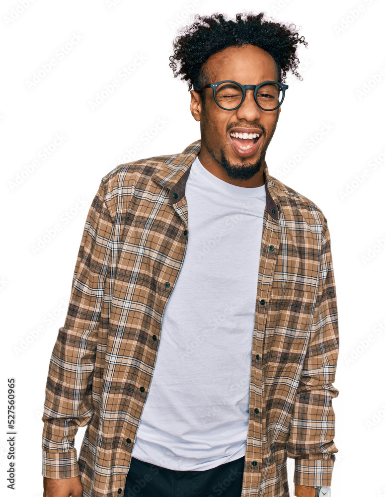 Young african american man with beard wearing casual clothes and glasses winking looking at the camera with sexy expression, cheerful and happy face. Young african american man with beard wearing casual clothes and glasses winking looking at the camera with sexy expression, cheerful and happy face.