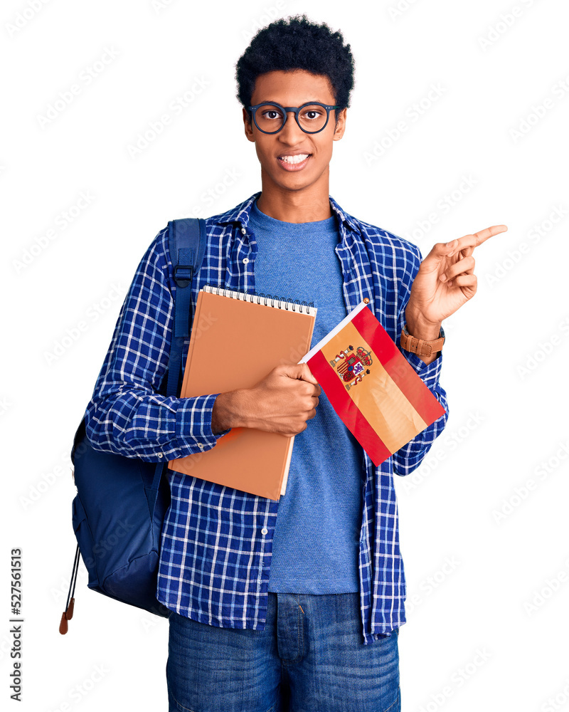 Young african american man wearing student backpack holding spanish flag smiling happy pointing with hand and finger to the side Young african american man wearing student backpack holding spanish flag smiling happy pointing with hand and finger to the side
