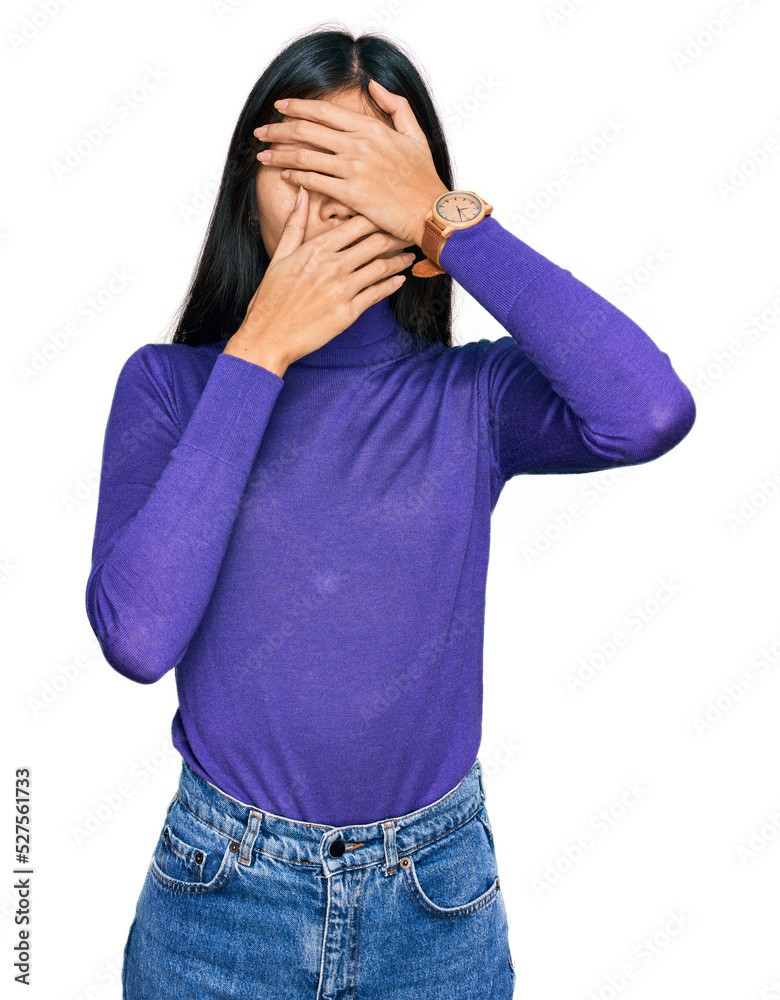 Beautiful young asian woman wearing casual clothes covering eyes and mouth with hands, surprised and shocked. hiding emotion