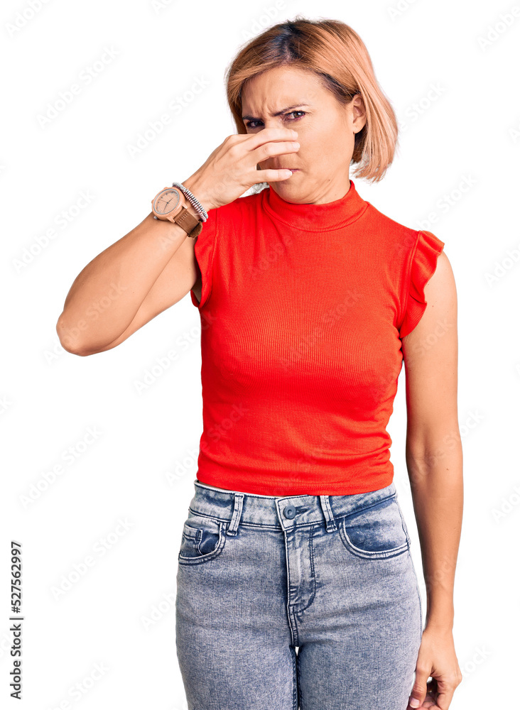 Young blonde woman wearing casual clothes smelling something stinky and disgusting, intolerable smell, holding breath with fingers on nose. bad smell Young blonde woman wearing casual clothes smelling something stinky and disgusting, intolerable smell, holding breath with fingers on nose. bad smell