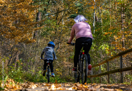 A mother with kid rides a bike through the autumn landscape